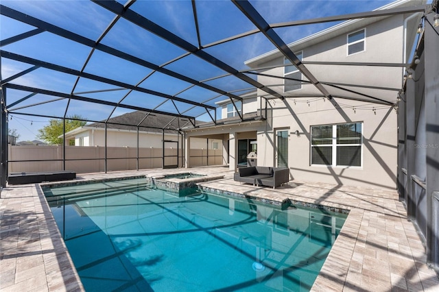 view of pool with a patio area, a pool with connected hot tub, a lanai, and fence