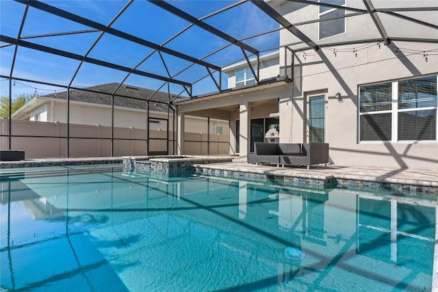 view of pool featuring a pool with connected hot tub, ceiling fan, glass enclosure, outdoor lounge area, and a patio