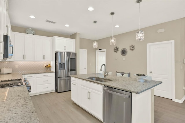 kitchen with visible vents, light stone countertops, decorative backsplash, appliances with stainless steel finishes, and a sink