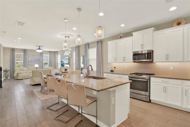 kitchen with tasteful backsplash, light stone countertops, stainless steel appliances, and a sink