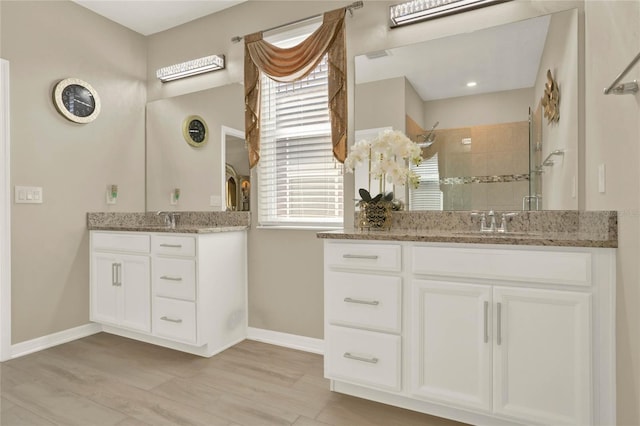 full bathroom with a shower stall, two vanities, wood finished floors, and a sink