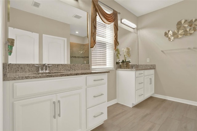 bathroom featuring visible vents, tiled shower, wood finished floors, and a sink
