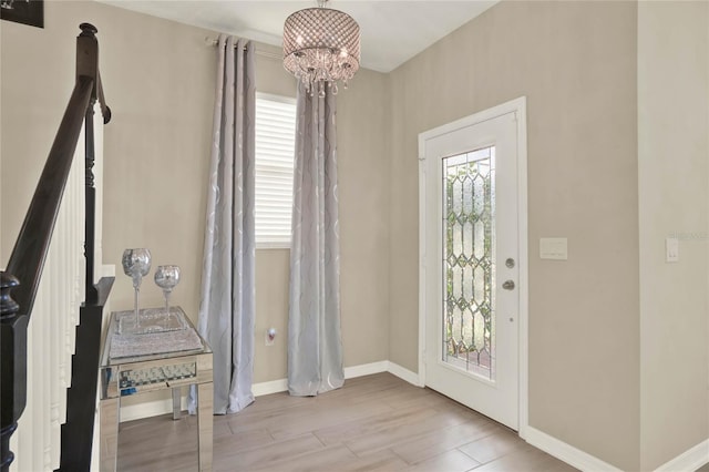 foyer featuring baseboards, a notable chandelier, and wood finished floors