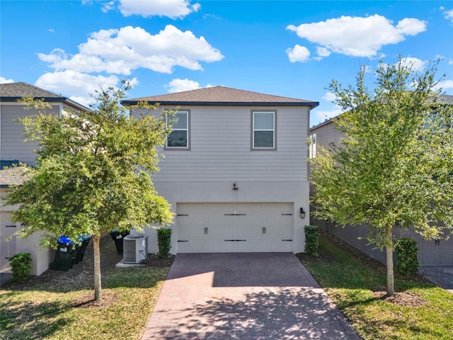 view of front of home featuring decorative driveway, central AC unit, fence, and an attached garage