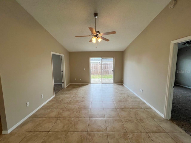 empty room with a textured ceiling, light tile patterned floors, baseboards, ceiling fan, and vaulted ceiling