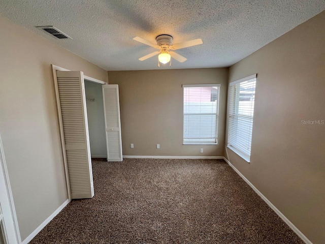 unfurnished bedroom with visible vents, carpet flooring, a textured ceiling, and baseboards