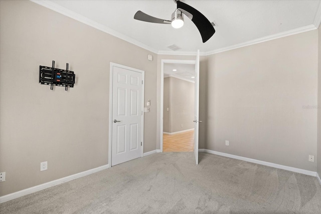 unfurnished bedroom featuring crown molding, a ceiling fan, visible vents, carpet floors, and baseboards