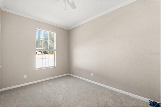 carpeted spare room with crown molding, ceiling fan, and baseboards