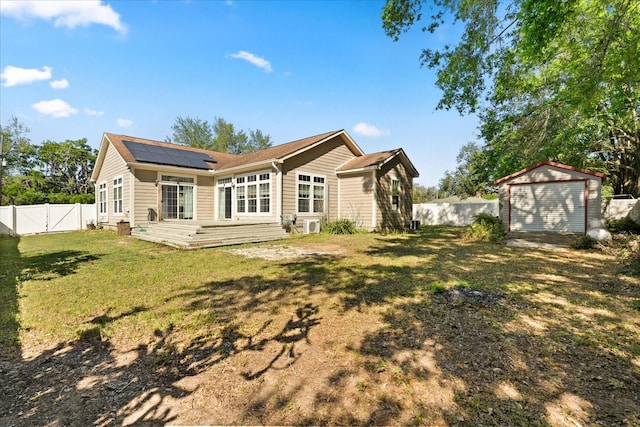 rear view of house featuring a fenced backyard, an outdoor structure, solar panels, a gate, and a garage