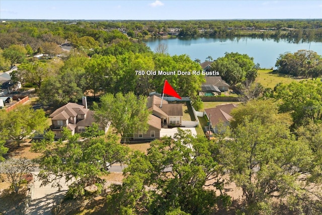 drone / aerial view featuring a view of trees, a residential view, and a water view