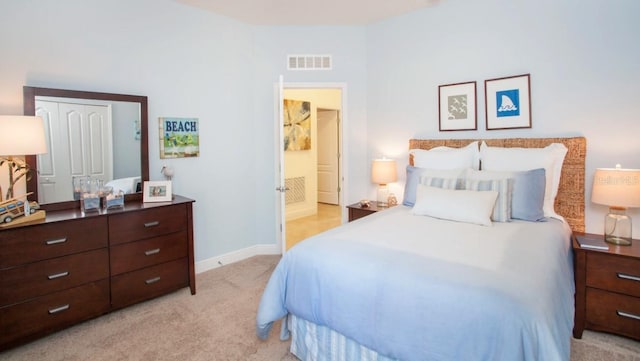 bedroom with connected bathroom, baseboards, visible vents, and light carpet