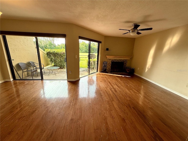 1886 Saint Andrews Pl Unit 1886, Longwood, FL 32779 - unfurnished living room with wood finished floors, ceiling fan, baseboards, a fireplace with raised hearth, and a textured ceiling