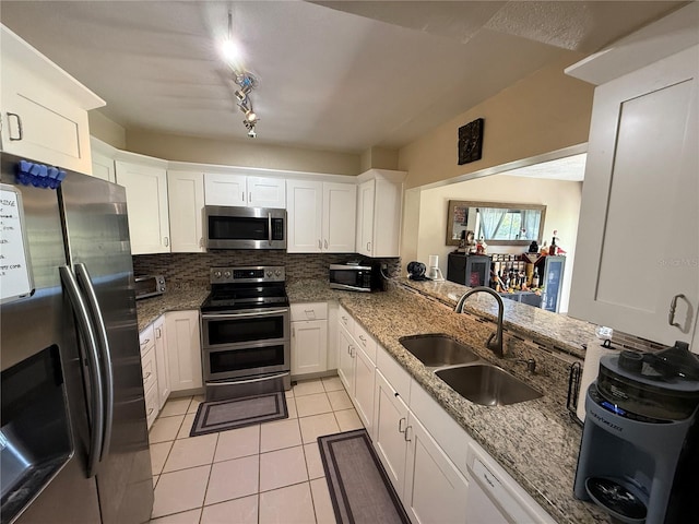 1886 Saint Andrews Pl Unit 1886, Longwood, FL 32779 - kitchen with stainless steel appliances, a sink, light tile patterned floors, white cabinetry, and tasteful backsplash