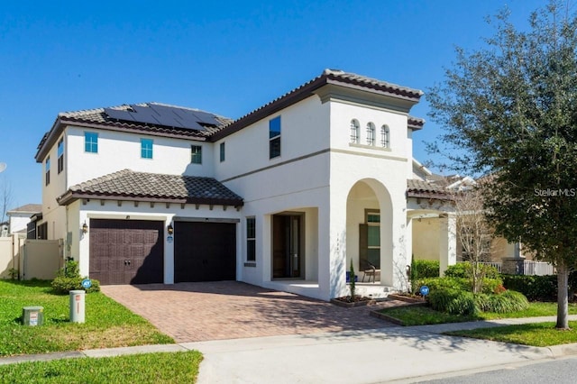 14645 Scott Key Dr, Winter Garden, FL 34787 - mediterranean / spanish home featuring an attached garage, stucco siding, a tiled roof, decorative driveway, and roof mounted solar panels