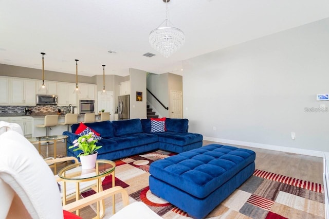 14645 Scott Key Dr, Winter Garden, FL 34787 - living room with baseboards, visible vents, an inviting chandelier, stairs, and light wood-type flooring