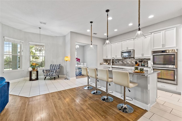 14645 Scott Key Dr, Winter Garden, FL 34787 - kitchen featuring backsplash, light stone counters, stainless steel appliances, light tile patterned flooring, and white cabinetry