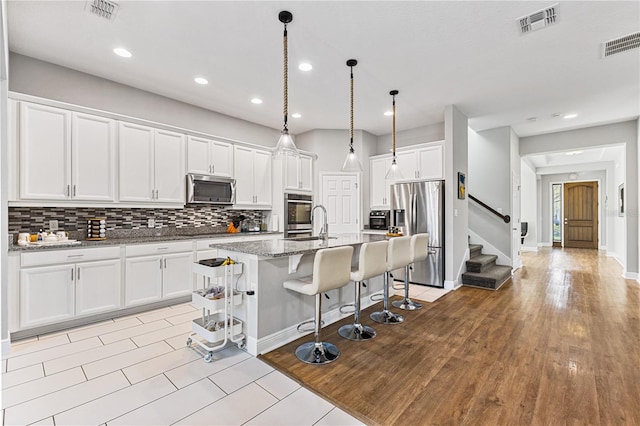 14645 Scott Key Dr, Winter Garden, FL 34787 - kitchen with tasteful backsplash, visible vents, a kitchen bar, white cabinets, and stainless steel appliances