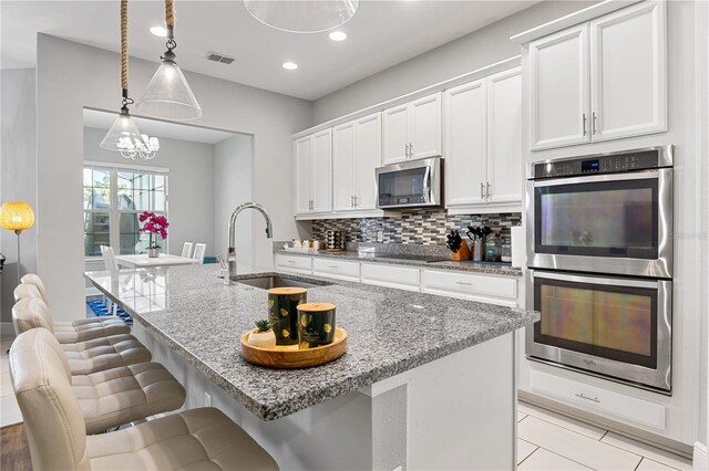 14645 Scott Key Dr, Winter Garden, FL 34787 - kitchen featuring visible vents, a sink, stainless steel appliances, white cabinets, and decorative backsplash