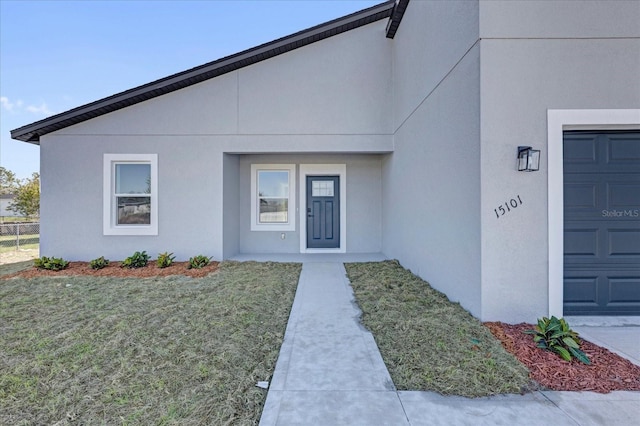 view of exterior entry featuring stucco siding and a yard