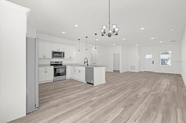 kitchen featuring light wood-style flooring, open floor plan, stainless steel appliances, a peninsula, and an inviting chandelier