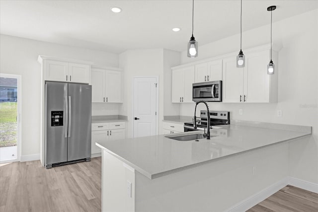 kitchen with a sink, white cabinetry, appliances with stainless steel finishes, a peninsula, and light countertops