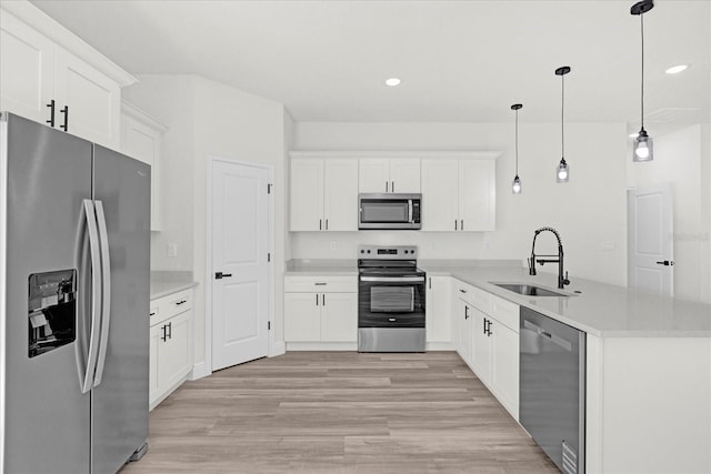 kitchen featuring light wood-type flooring, light countertops, a peninsula, stainless steel appliances, and a sink
