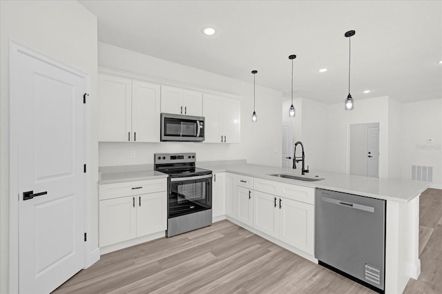 kitchen with visible vents, a sink, stainless steel appliances, a peninsula, and light wood finished floors