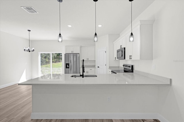 kitchen featuring visible vents, a sink, stainless steel appliances, white cabinets, and light countertops