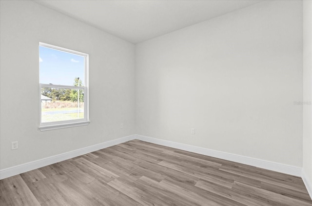 spare room featuring baseboards and wood finished floors