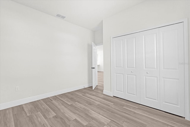 unfurnished bedroom featuring light wood finished floors, visible vents, a closet, and baseboards