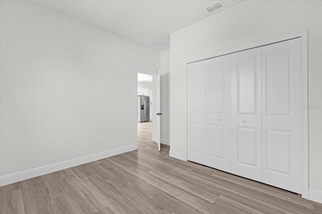 unfurnished bedroom with visible vents, stainless steel fridge, baseboards, and wood finished floors
