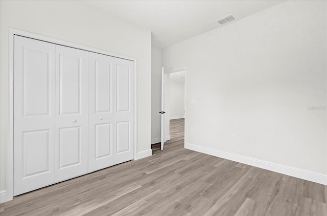 unfurnished bedroom featuring a closet, visible vents, light wood-type flooring, and baseboards
