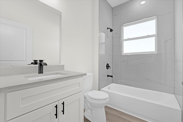 bathroom with tub / shower combination, toilet, wood finished floors, and vanity