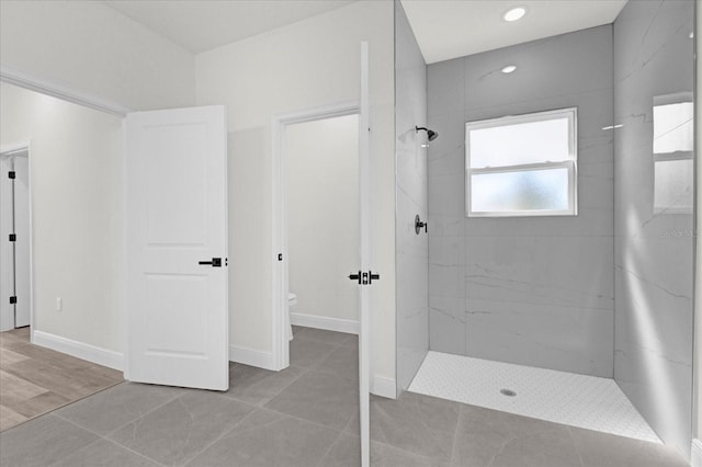 full bathroom featuring toilet, baseboards, and a tile shower