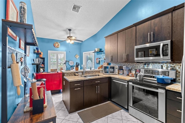 10589 Pelican Dr, Wellington, FL 33414 - kitchen with visible vents, a sink, appliances with stainless steel finishes, a peninsula, and lofted ceiling