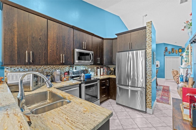 10589 Pelican Dr, Wellington, FL 33414 - kitchen with light tile patterned floors, lofted ceiling, a sink, stainless steel appliances, and dark brown cabinets