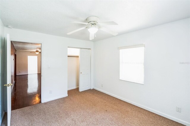 unfurnished bedroom with a closet, baseboards, ceiling fan, and carpet flooring
