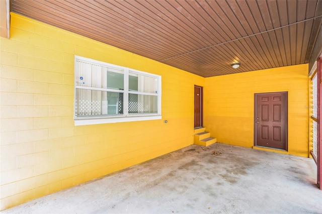 view of exterior entry featuring concrete block siding and a patio