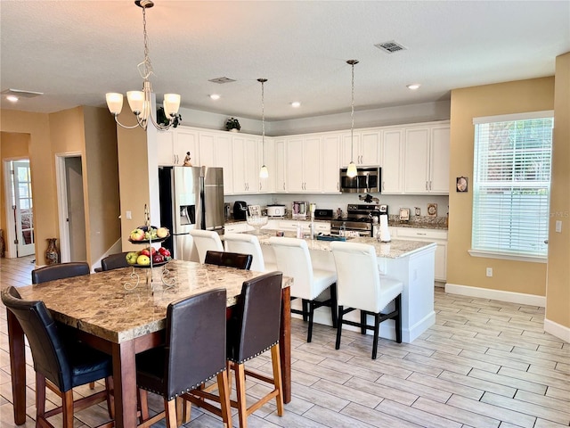 1337 Ash Tree Cv, Casselberry, FL 32707 - kitchen with a kitchen bar, a center island with sink, white cabinetry, and stainless steel appliances