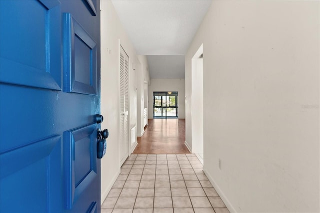 corridor featuring light tile patterned floors and baseboards