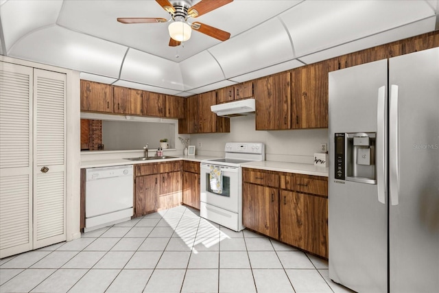 kitchen with under cabinet range hood, a sink, white appliances, light countertops, and light tile patterned floors