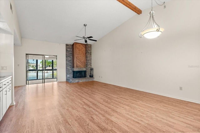 unfurnished living room with light wood-type flooring, beam ceiling, high vaulted ceiling, a ceiling fan, and a brick fireplace