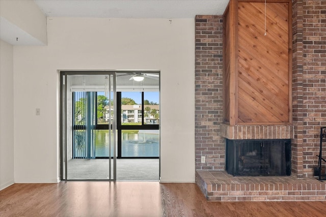 unfurnished living room with baseboards, a fireplace, wood finished floors, and a ceiling fan