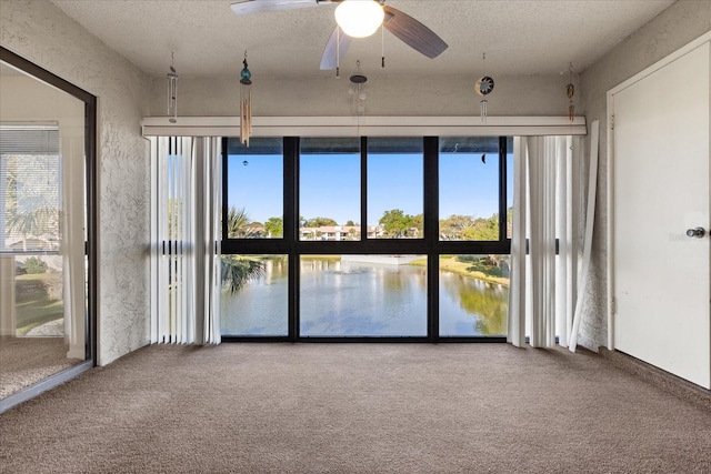spare room with a textured ceiling, carpet, and a ceiling fan