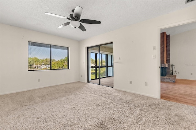 carpeted spare room featuring visible vents, baseboards, a textured ceiling, and ceiling fan