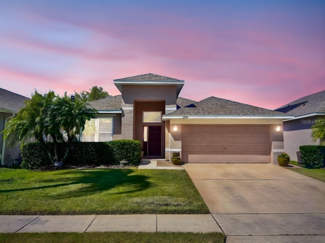 prairie-style home featuring a front yard, concrete driveway, stucco siding, and an attached garage