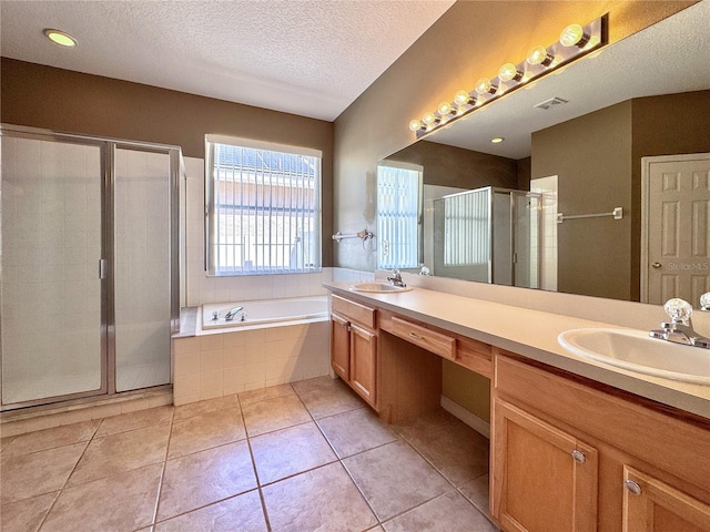 2519 Cypress Trace Cir, Orlando, FL 32825 - bathroom with double vanity, a shower stall, a bath, a textured ceiling, and tile patterned flooring