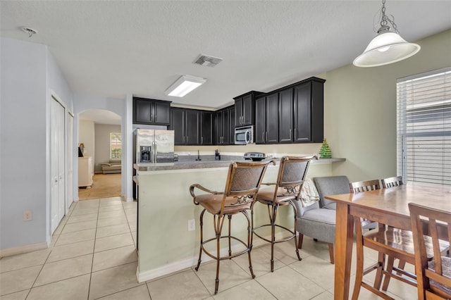 5910 Windsong Oak Dr, Leesburg, FL 34748 - kitchen featuring visible vents, light countertops, appliances with stainless steel finishes, dark cabinetry, and arched walkways