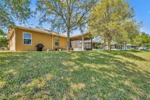 5910 Windsong Oak Dr, Leesburg, FL 34748 - back of property featuring central air condition unit, a yard, a sunroom, and stucco siding