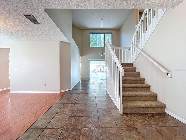 358 Morning Creek Cir, Apopka, FL 32712 - staircase featuring visible vents, ceiling fan, baseboards, a towering ceiling, and a textured ceiling